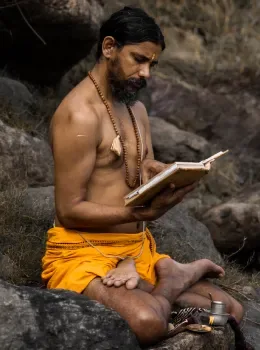 Yogi Vishnu Panigrahi reading a sacred yoga scripture outdoors in the Himalayas