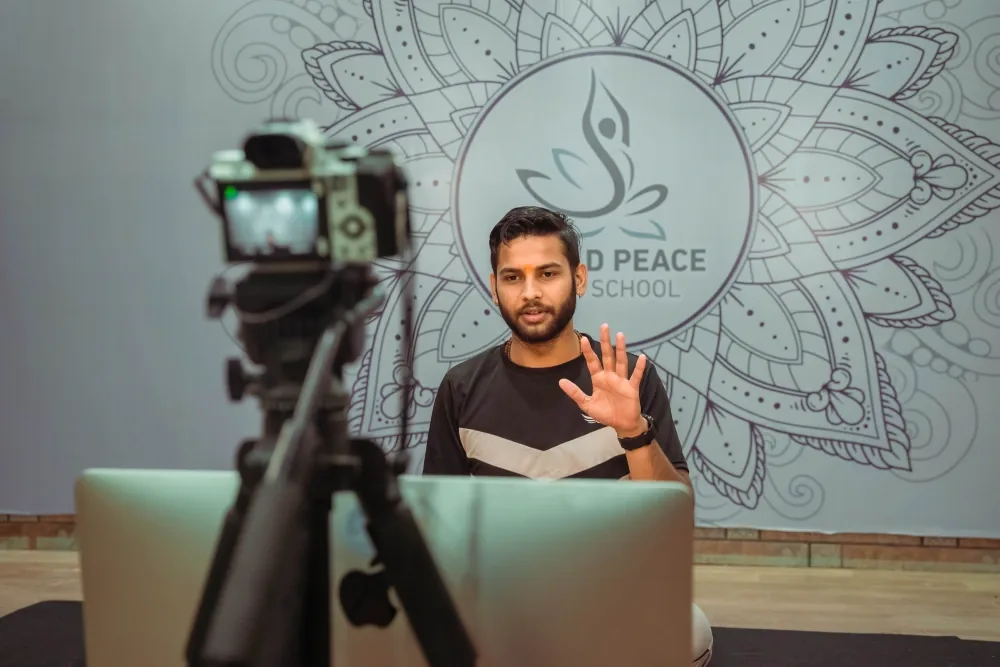 Instructor teaching a live online yoga class to camera with a laptop