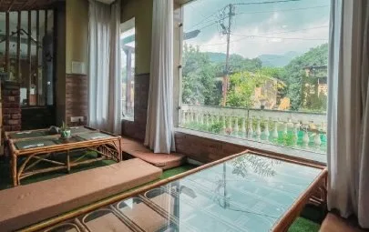 Low glass tables and floor cushions by a window with hill views
