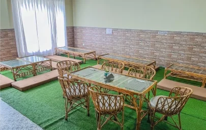 Rows of low tables and cane chairs against a brick wall