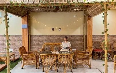 A guest reading under a thatched bamboo canopy with fairy lights