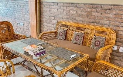 A cane sofa and glass-topped table against a brick wall