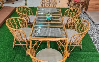 A cane table set for six on green matting