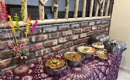 Vegetarian buffet dishes against a brick and wood wall