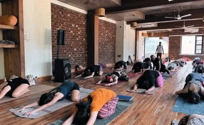 Students resting in child’s pose across the hall