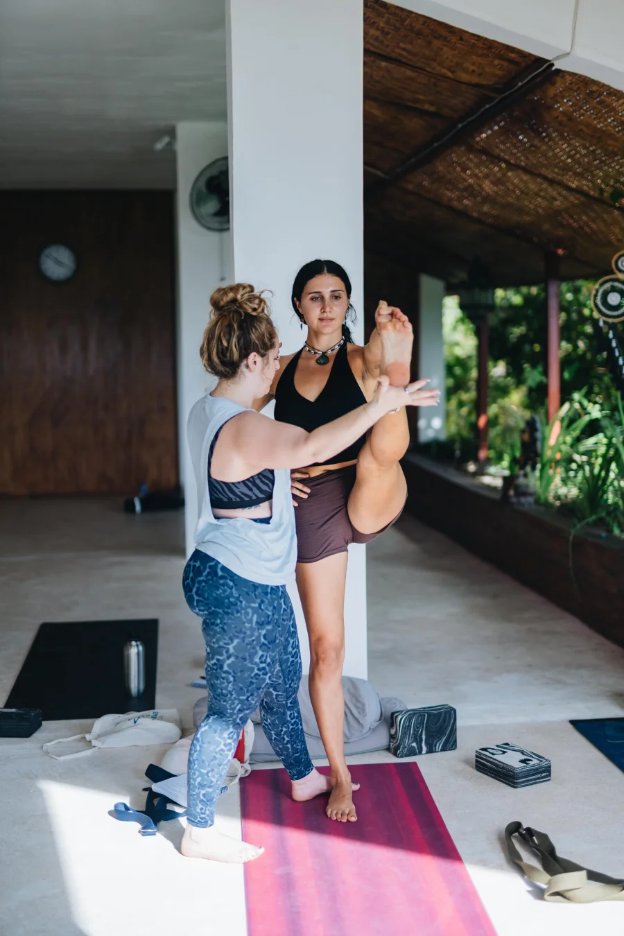 A teacher adjusting a student in a standing leg extension