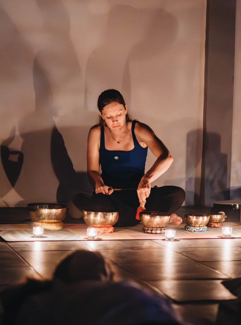 A student playing singing bowls by candlelight