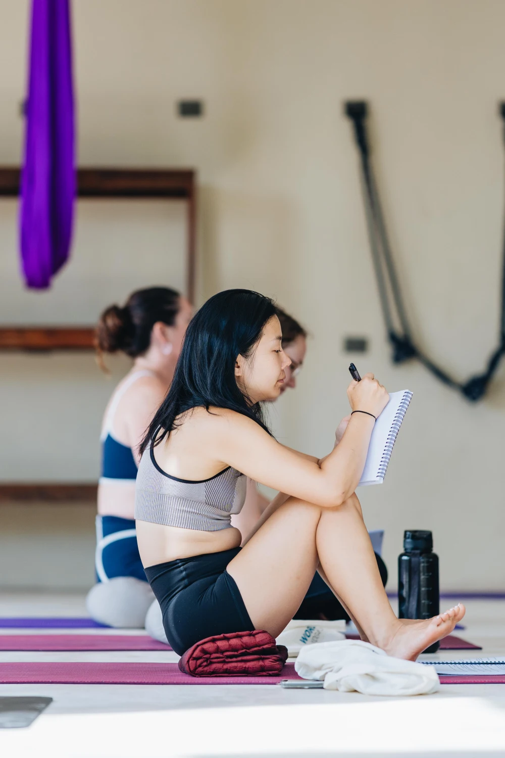 A student taking notes on her mat during a theory class