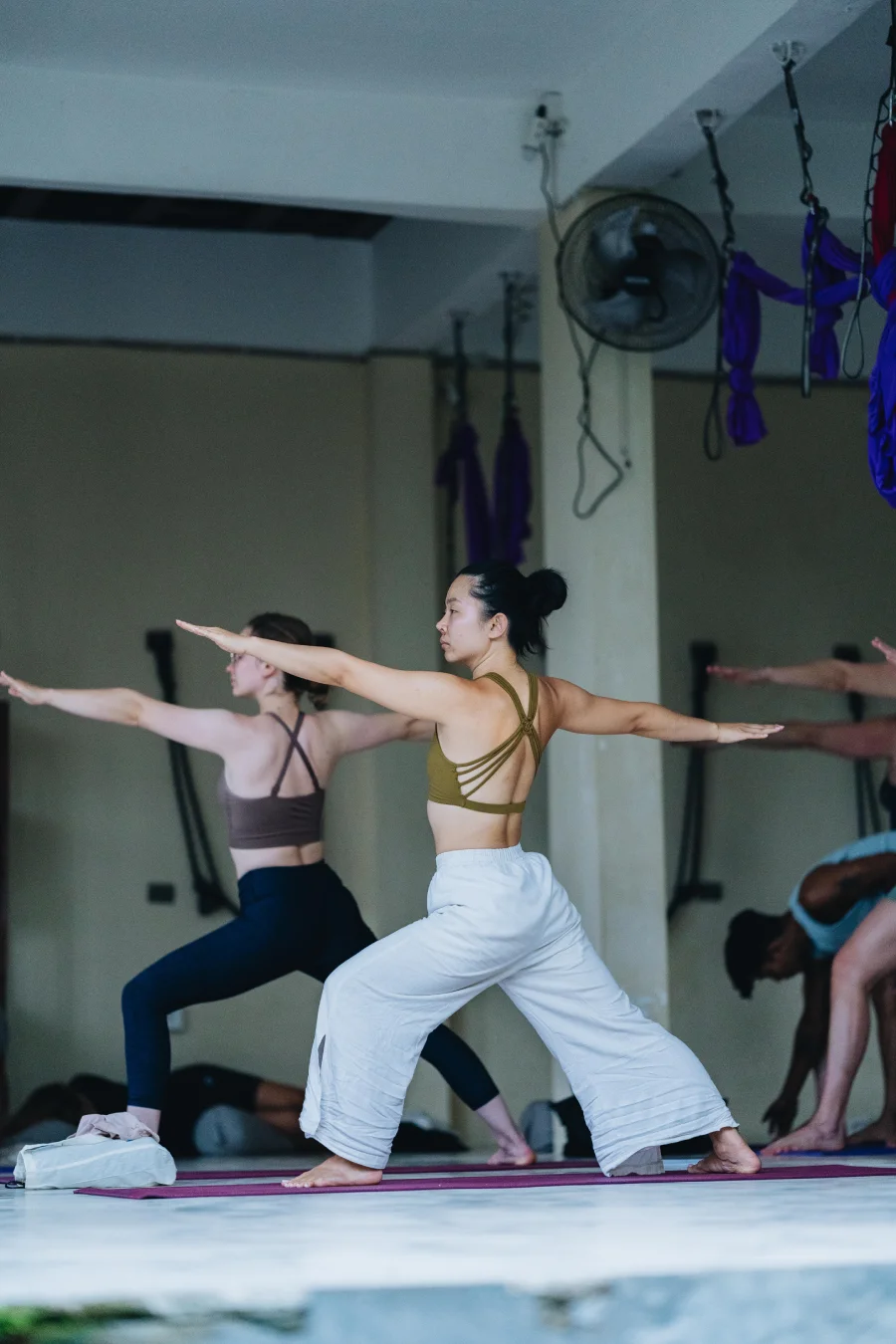 Students practising warrior two in the yoga shala