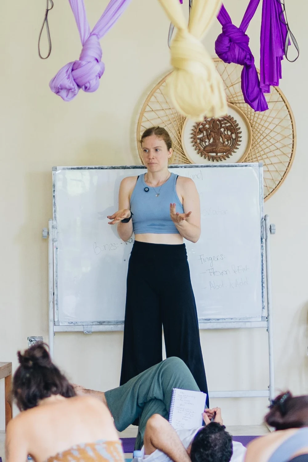 A teacher explaining anatomy at a whiteboard in the shala