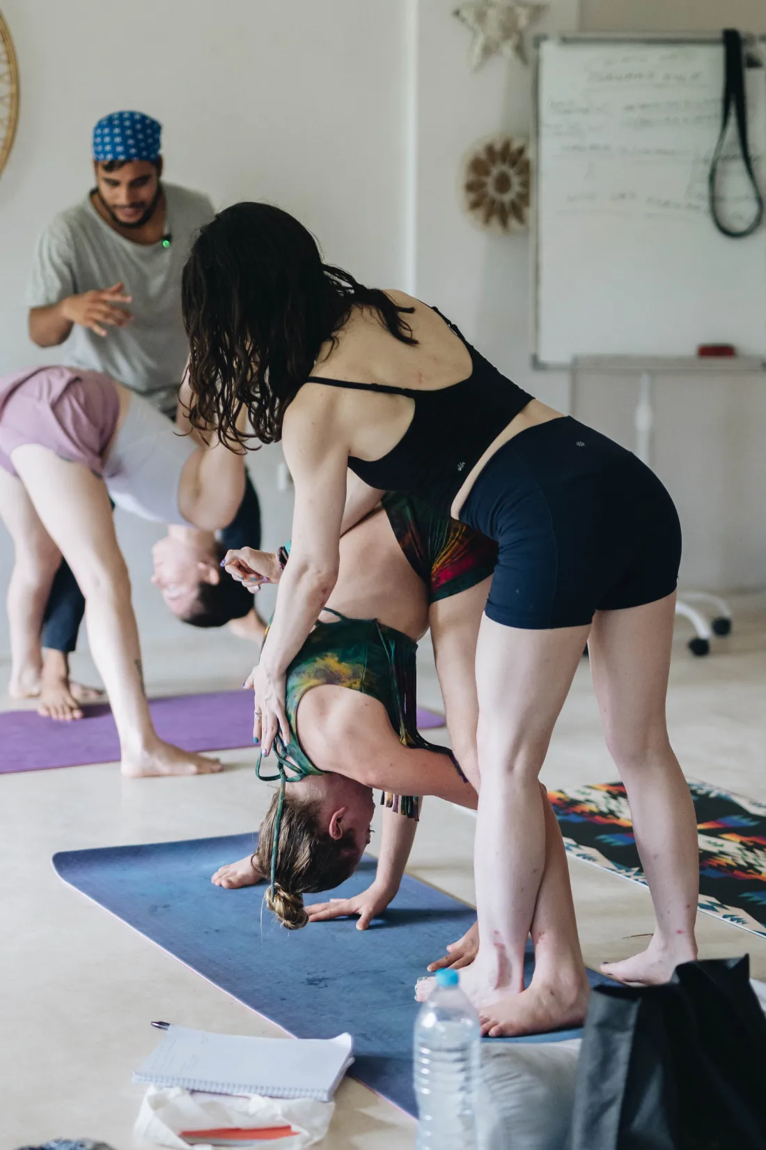A teacher adjusting a student in a standing forward fold
