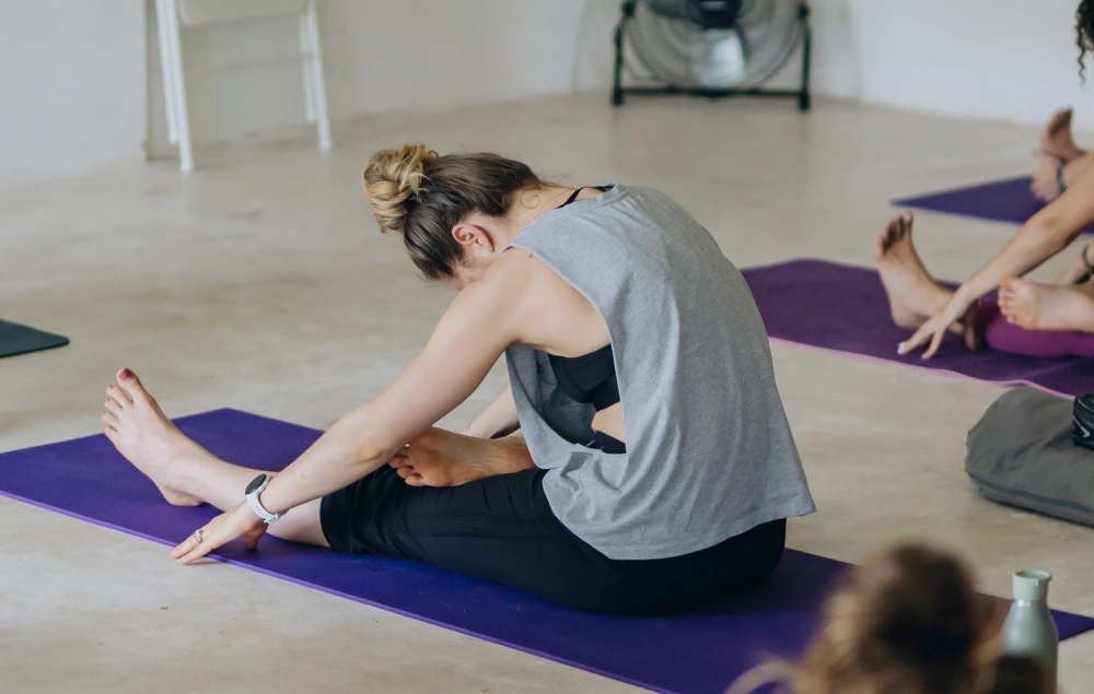 A student in a seated forward bend on a purple mat in the Bali shala