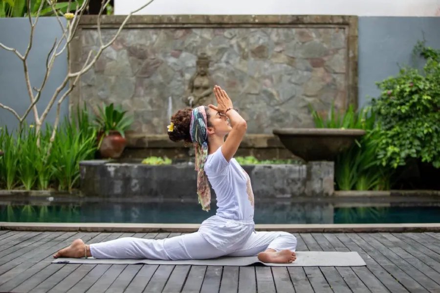 A student in white in a Kundalini prayer pose by the pool at the Bali school