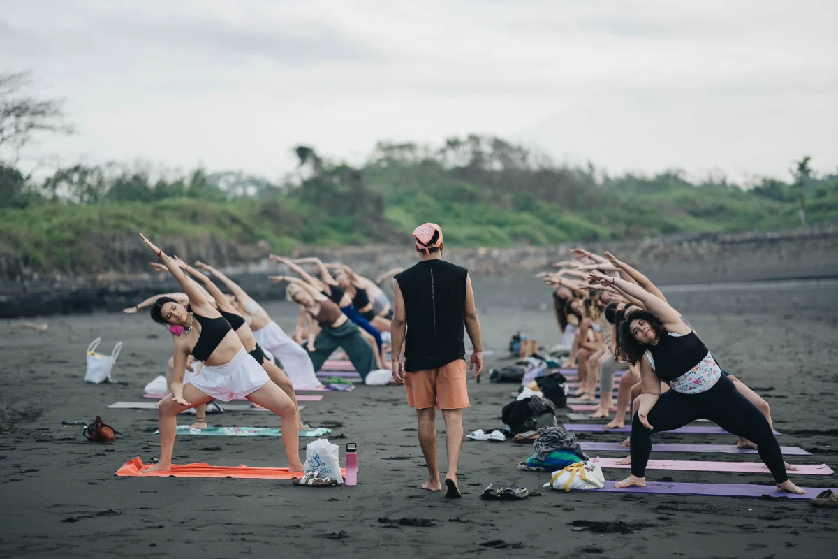 A teacher walking between rows of students in a side stretch on the beach