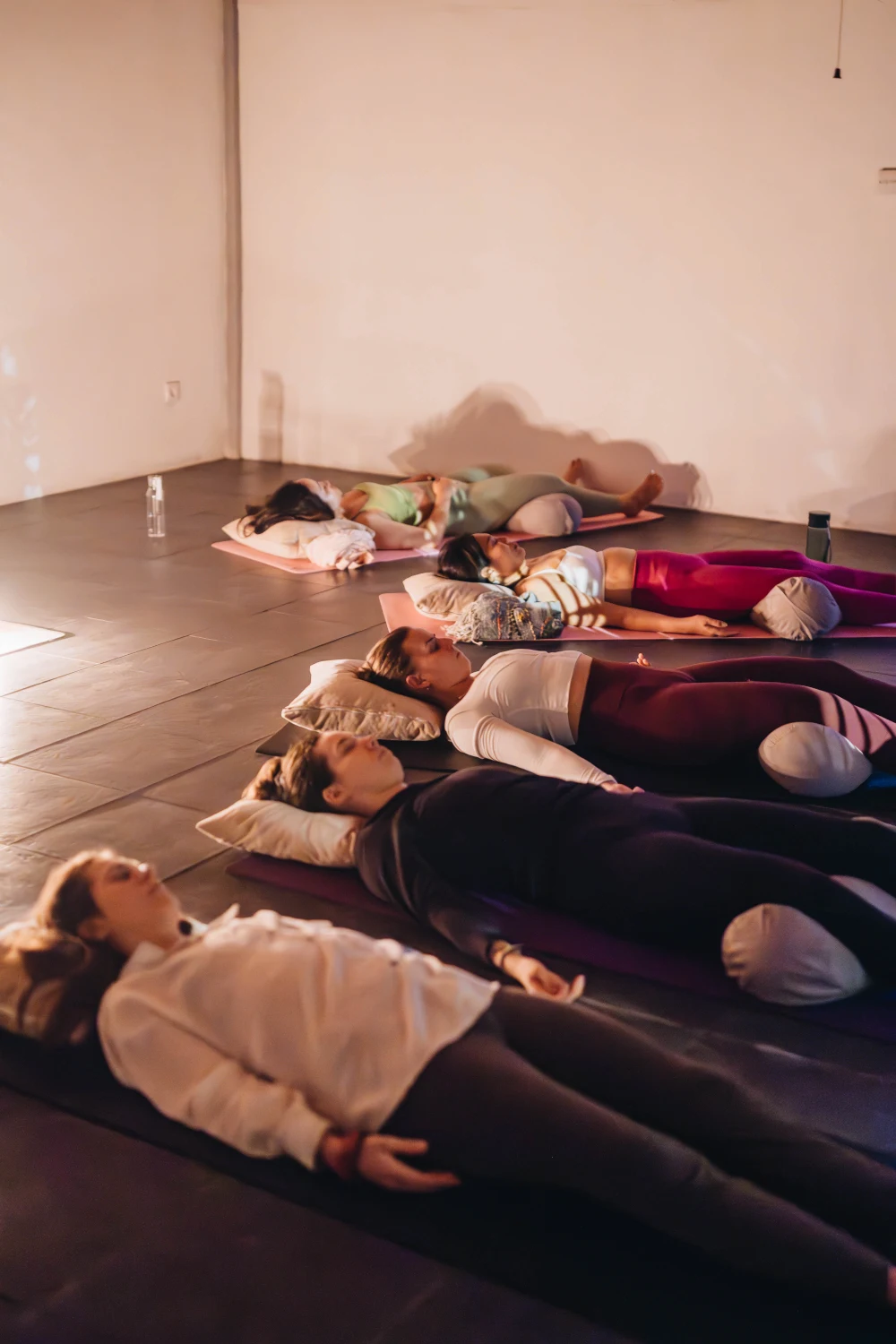 Students lying on mats with bolsters during a sound bath