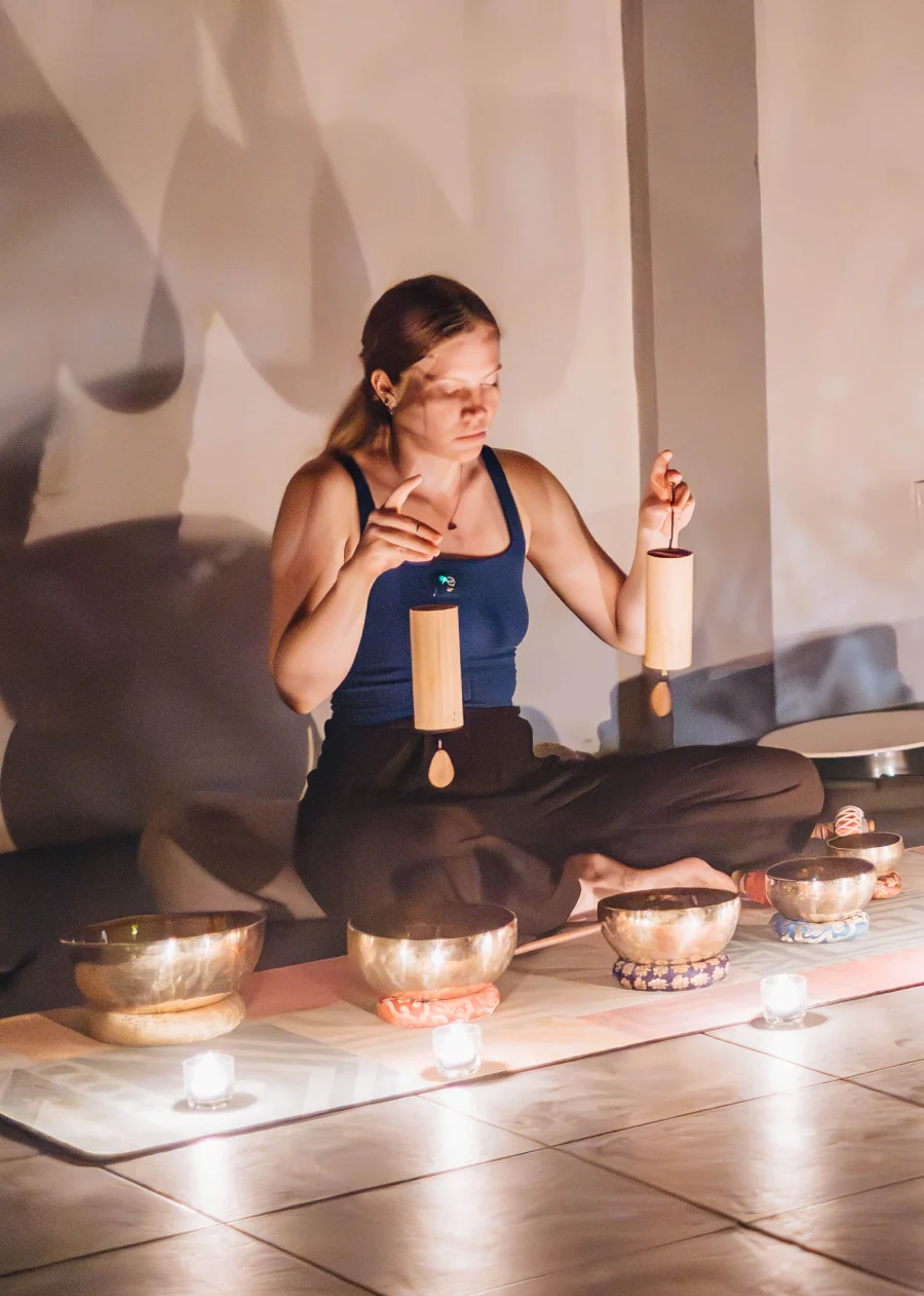 A student playing chimes behind a circle of singing bowls and candles