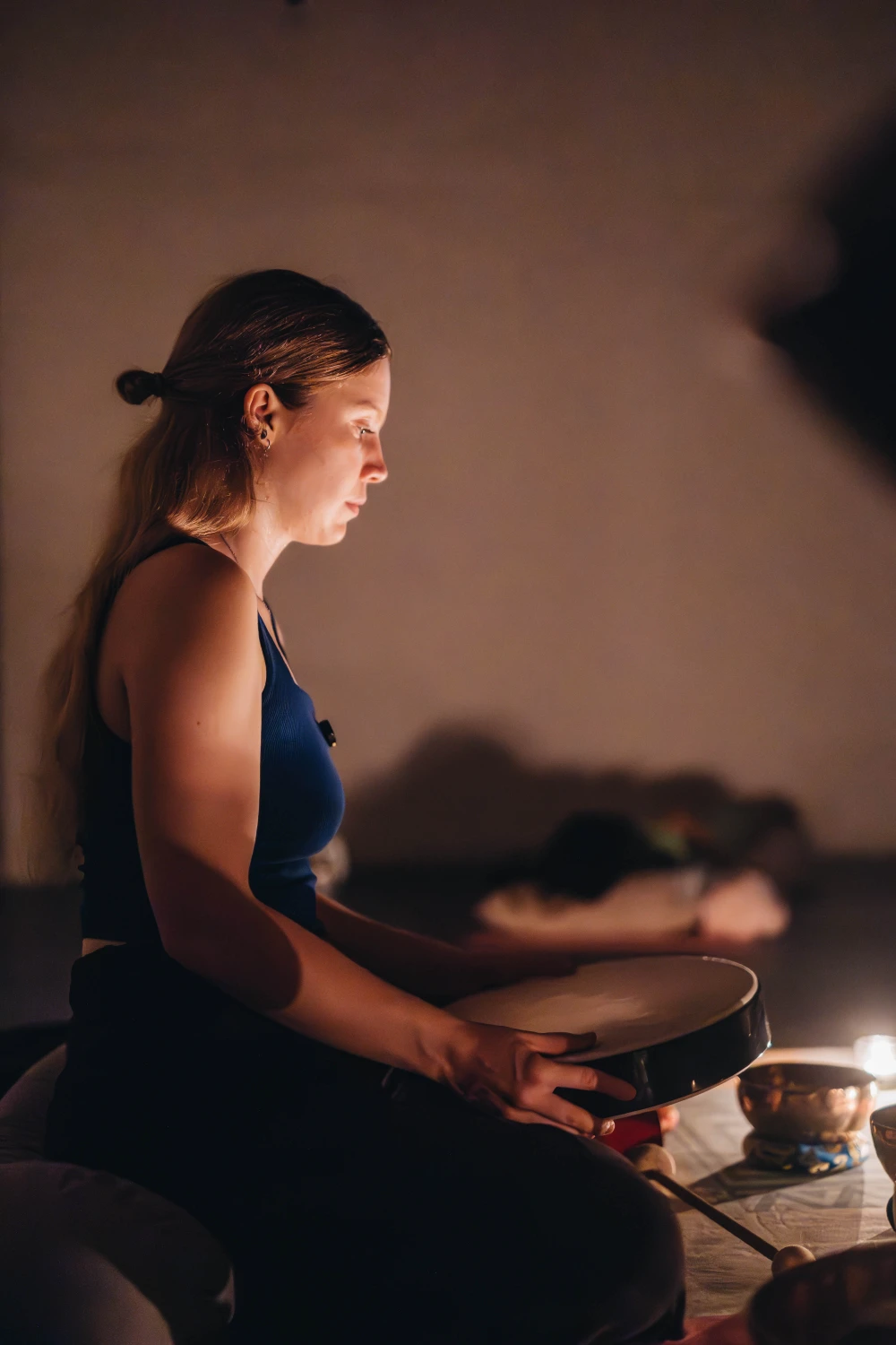 A student holding an ocean drum in candlelight