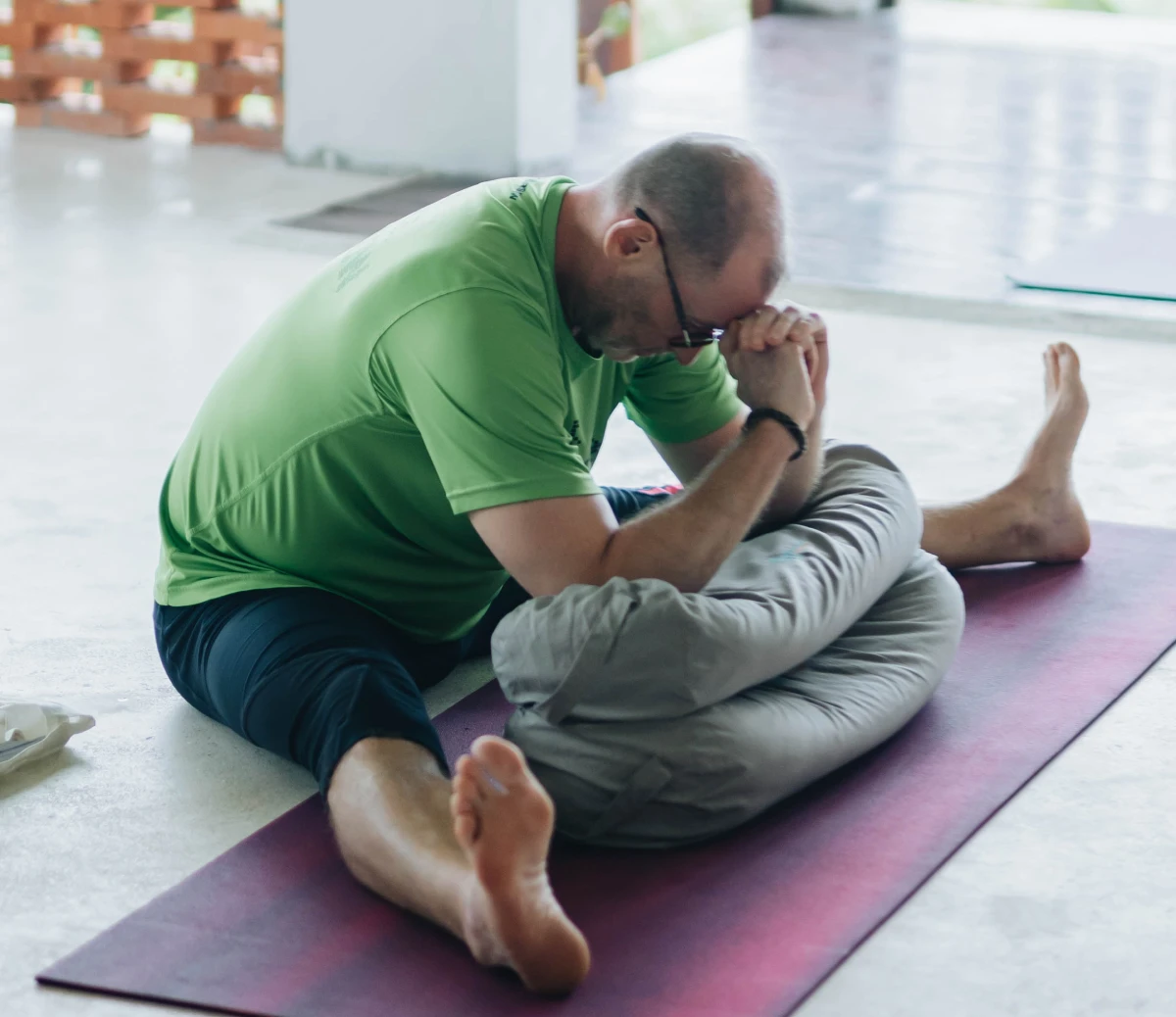 A student folding forward over a bolster in a seated Yin pose