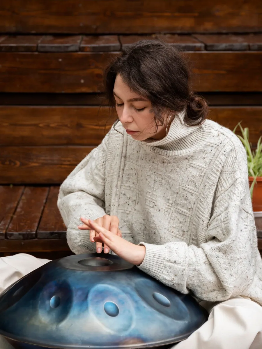 A student playing a blue hand pan with her fingertips