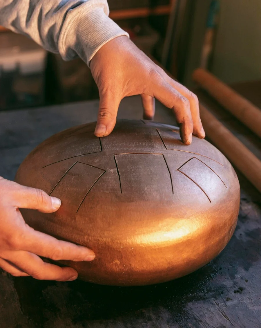 Hands resting on a copper tongue drum