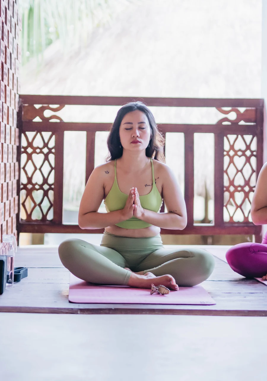 A student meditating cross-legged with hands in prayer at the Bali shala