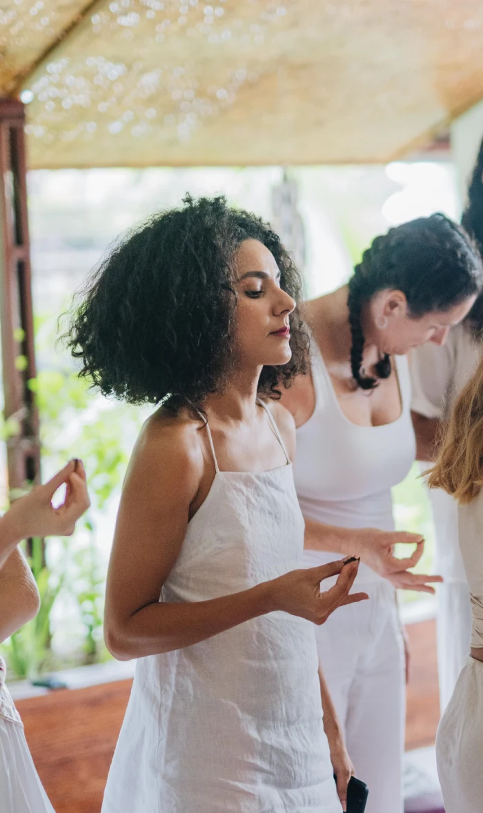 Students in white holding a mudra during an energy practice