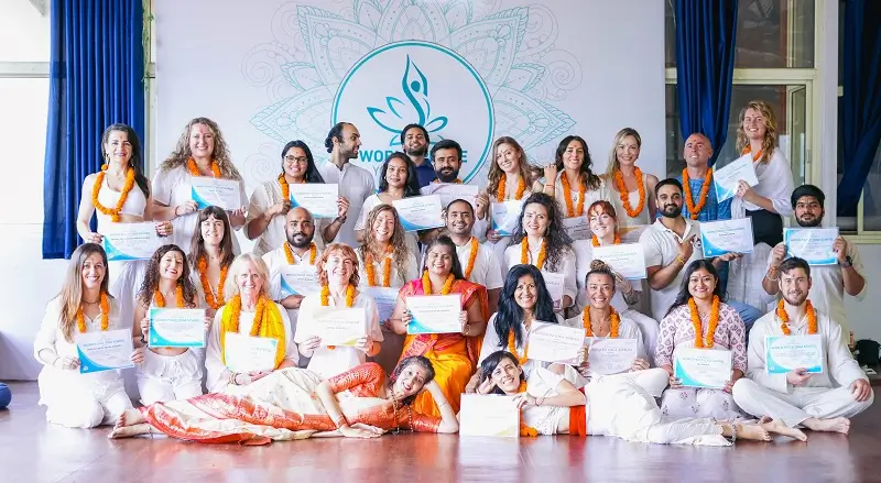 A large graduating batch holding their certificates in the yoga hall