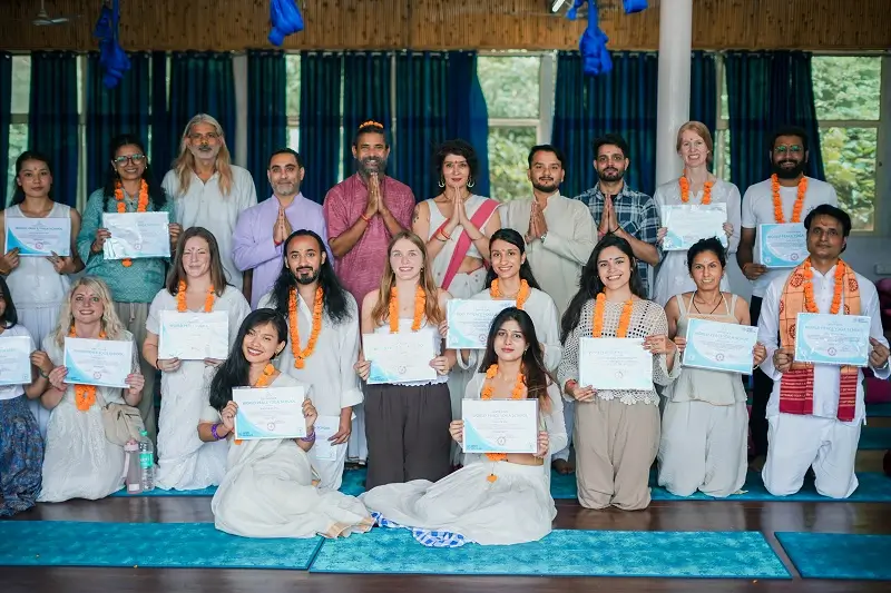 Teachers and graduates holding their yoga teacher training certificates