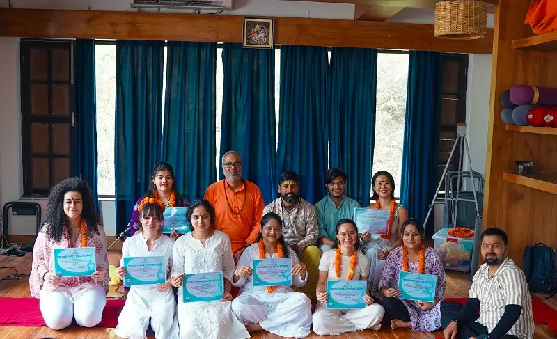 Graduates with certificates seated with their teachers in the yoga shala