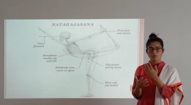 A teacher explaining Natarajasana alignment on a projected diagram