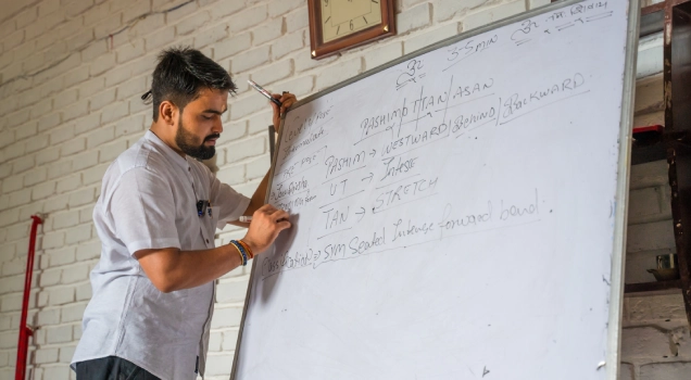 A teacher explaining asana names on a whiteboard