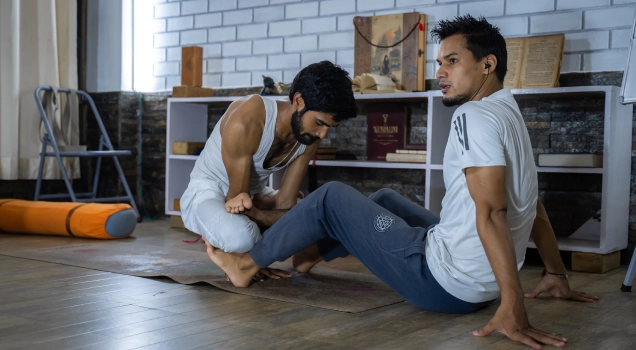 A teacher adjusting a student in a seated stretch