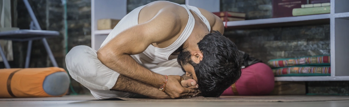 A student in a deep seated forward fold
