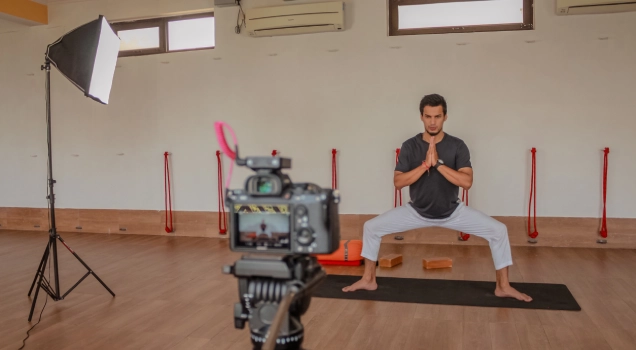 A teacher recording an online yoga class in front of a camera