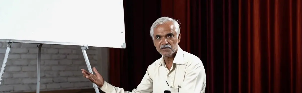 An Ayurveda teacher explaining a lesson beside a whiteboard