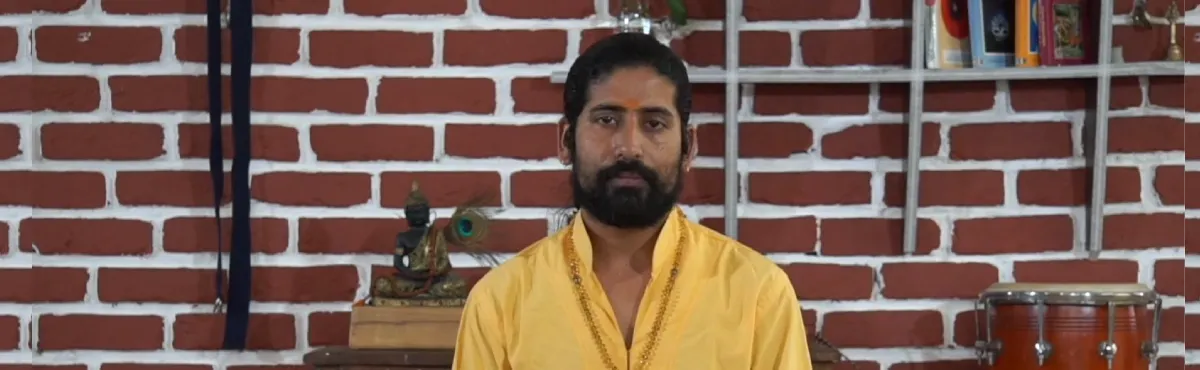 A Kundalini teacher seated in meditation in front of a brick wall
