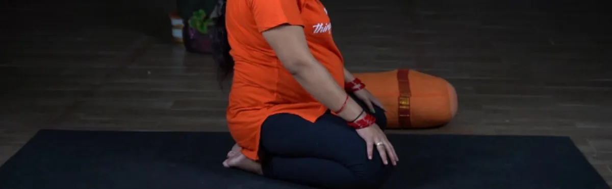 A pregnant woman kneeling in Vajrasana on a yoga mat
