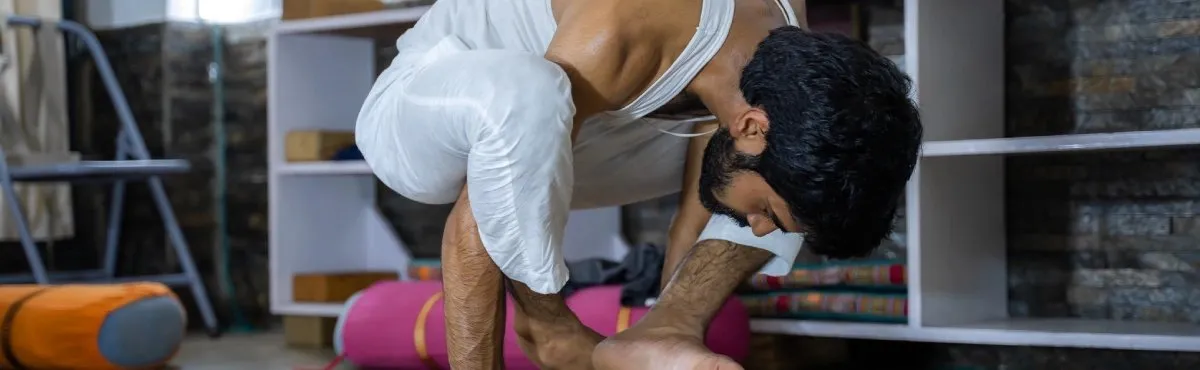 A student folding into a deep forward bend in the yoga hall