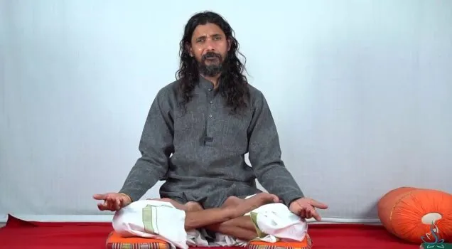 A teacher seated cross-legged guiding a Yoga Nidra session