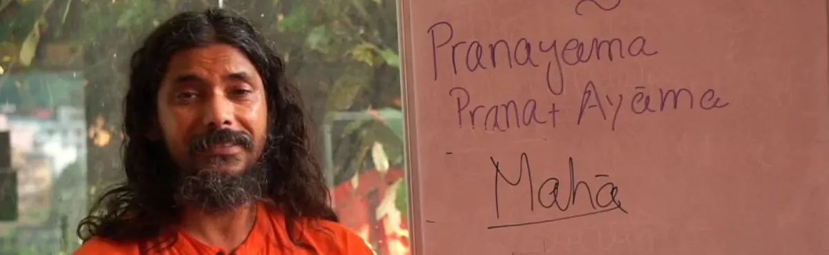 A teacher beside a whiteboard explaining the meaning of Pranayama