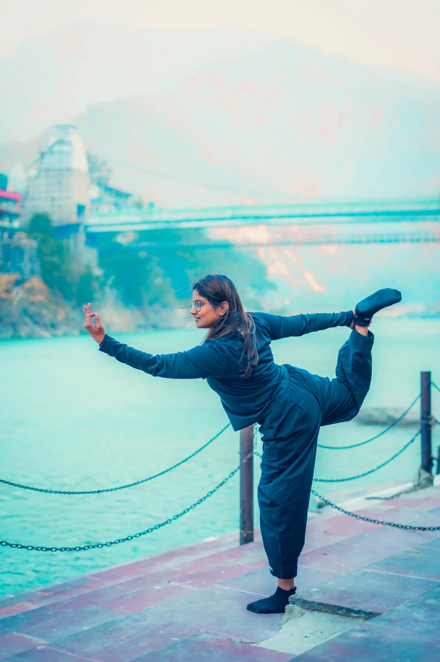 A student in dancer pose on the ghat beside the Ganga