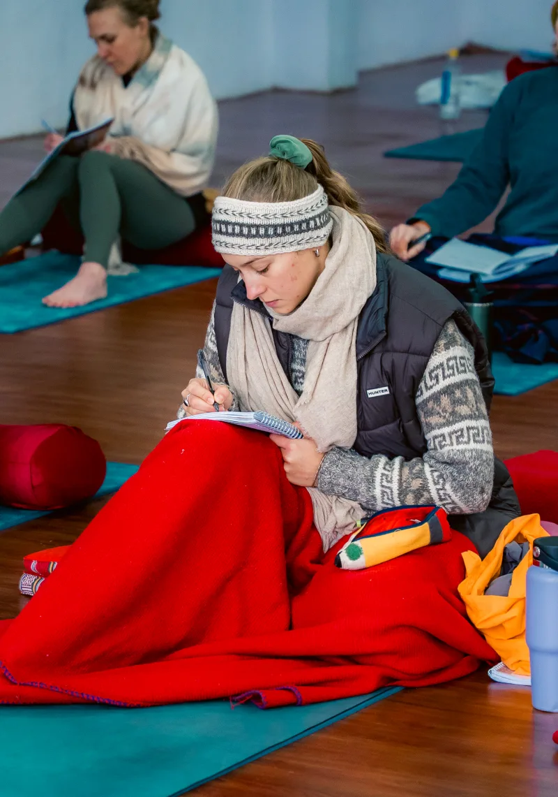 A student taking notes on her mat during a theory class
