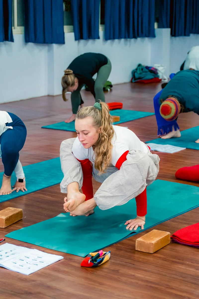 A student in a supported forward bend with yoga blocks during class