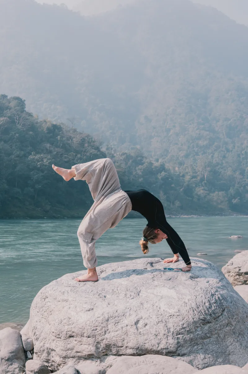 A student in a backbend on a rock by the Ganga