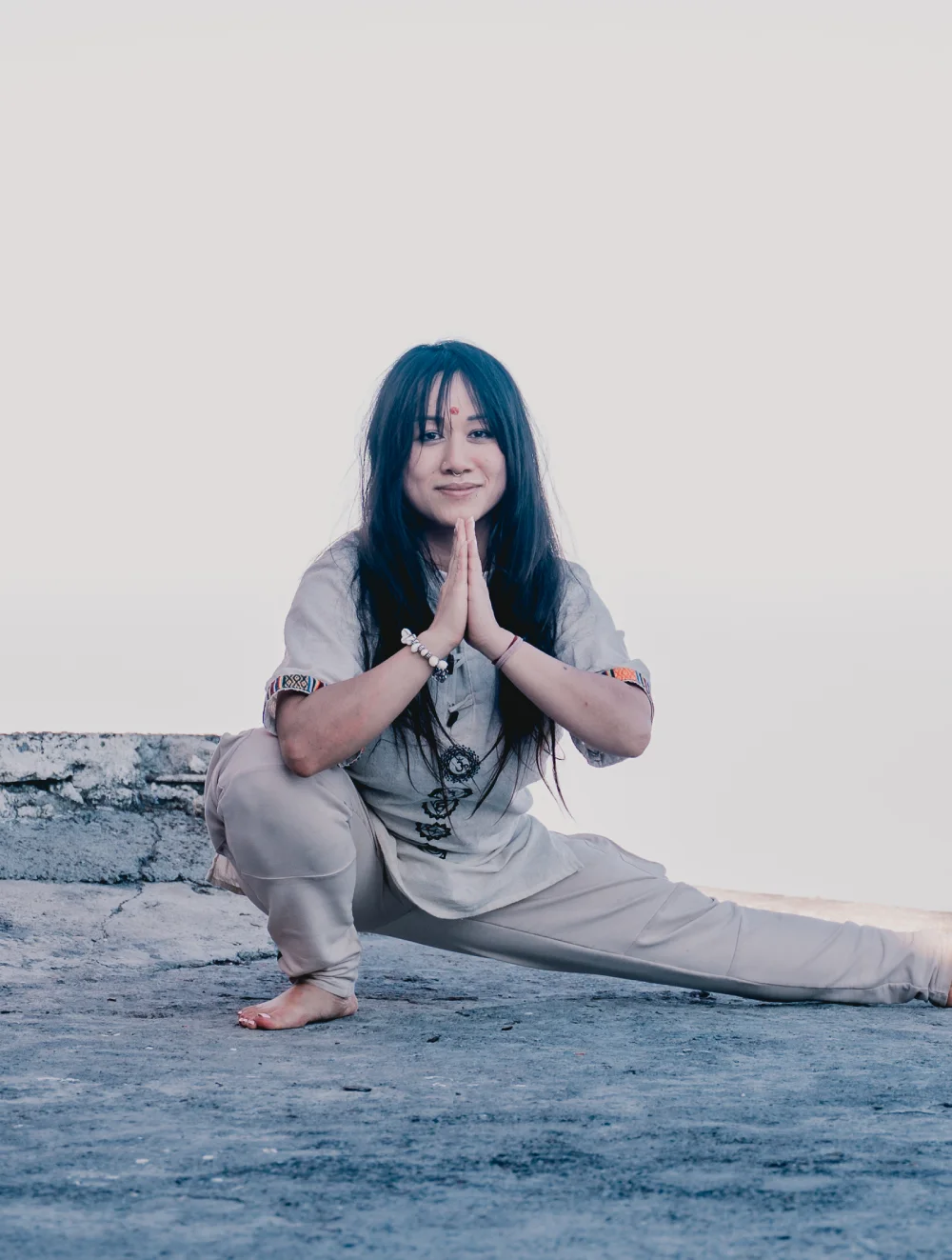 A student in a side lunge with palms joined on a rooftop