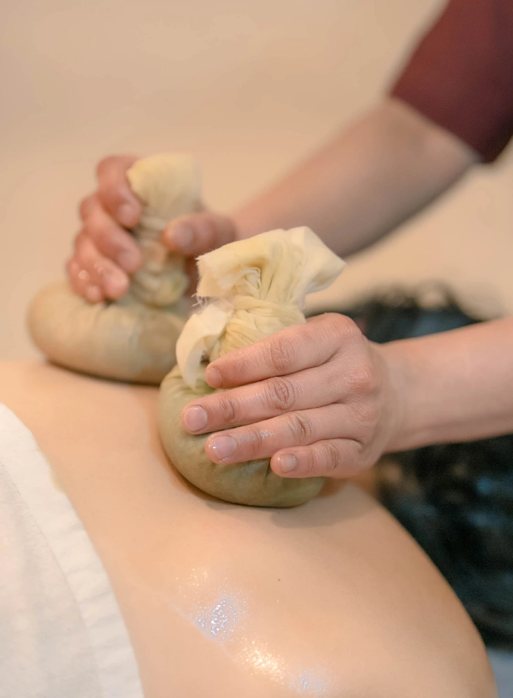 A therapist pressing warm herbal poultices during Ayurvedic massage