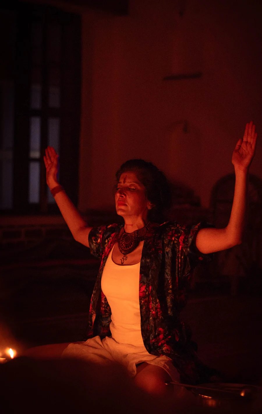 A student with raised palms in a candlelit healing meditation