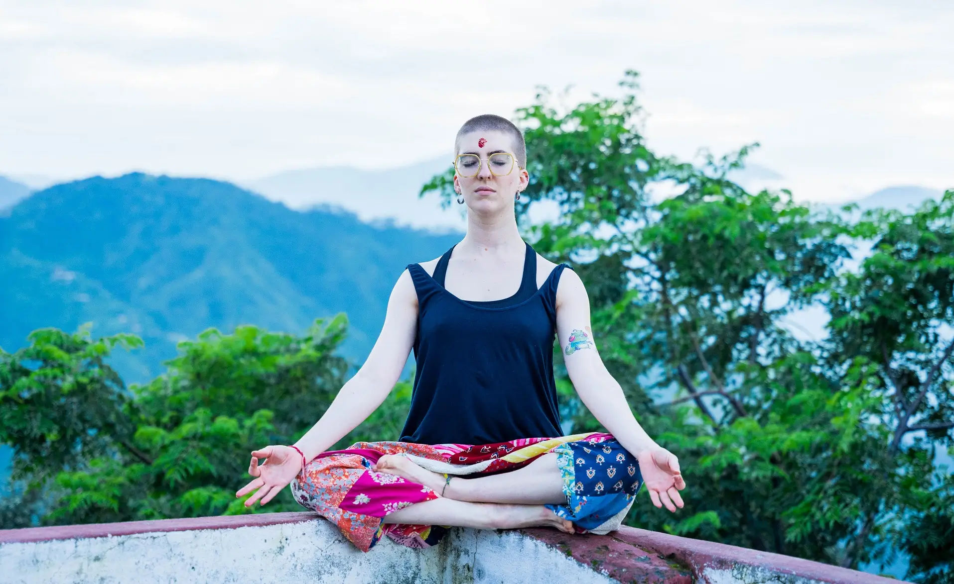 A student meditating in lotus pose above the Himalayan foothills