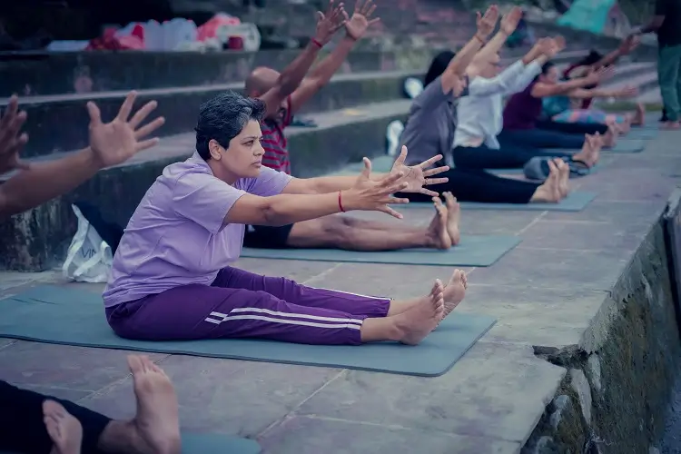 Students stretching their arms forward in a seated class by the river