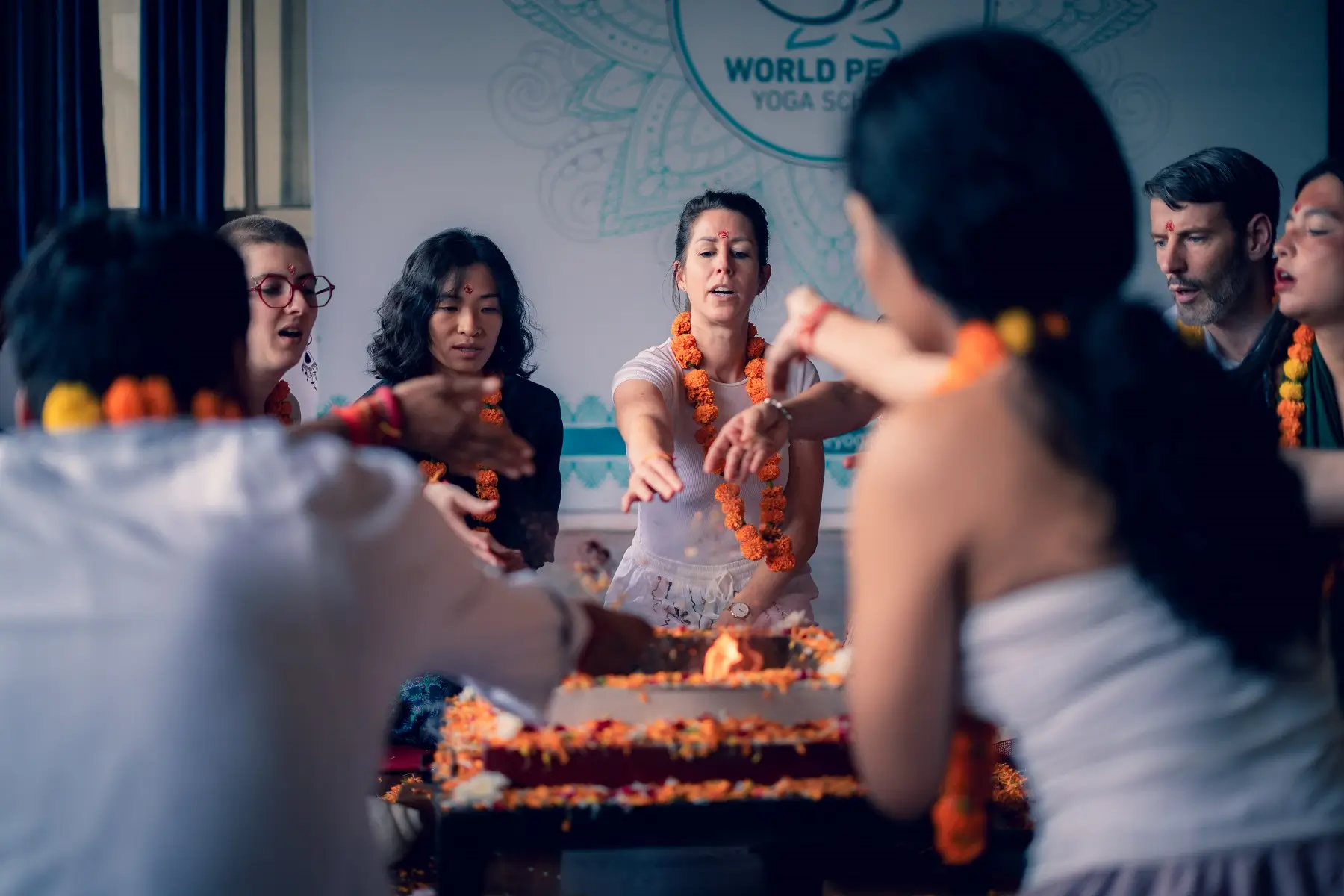 Students in marigold garlands offering to the fire during a havan ceremony